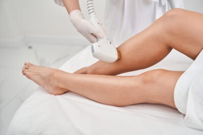 Top view close up cropped head of female legs while beauty specialist is doing epilation