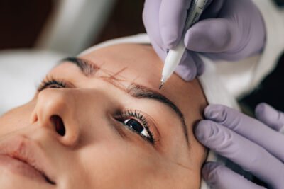 Beautician Addressing the Shape of the Brows Before Microblading.  Semi-Permanent Makeup