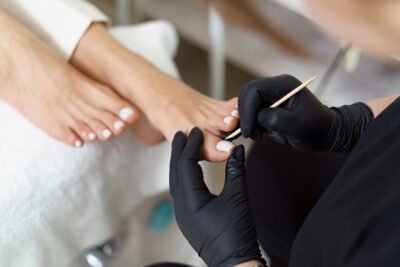 Specialist in beauty salon making french pedicure for female client. Relaxing at beauty salon, caring about nails.